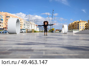 Young fit black woman on roller skates riding outdoors on urban street. Smiling girl with afro hairstyle rollerblading on sunny day. Black woman on roller skates riding outdoors on urban street. Стоковое фото, агентство Ingram Publishing / Фотобанк Лори