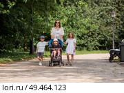 A family with three children. A mother with many children and toddlers in a summer park. Children are walking in the fresh air. Having many children and family values. Стоковое фото, фотограф Photojuli / Фотобанк Лори