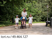 A family with three children. A mother with many children and toddlers in a summer park. Children are walking in the fresh air. Having many children and family values. Стоковое фото, фотограф Photojuli / Фотобанк Лори
