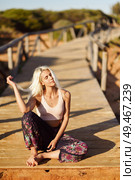Woman enjoying the sunset on a beautiful beach in Cadiz, Andalusia, Spain. Young female smiling sitting on wooden bridge.. Smiling woman enjoying the sunset on a beautiful beach. Стоковое фото, агентство Ingram Publishing / Фотобанк Лори