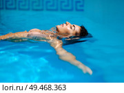Portrait of beautiful tanned woman in bikini relaxing in swimming pool spa. Hot summer day and bright sunny light. . Beautiful tanned woman in bikini relaxing in swimming pool. Стоковое фото, агентство Ingram Publishing / Фотобанк Лори