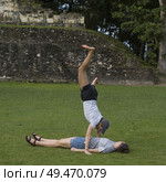 Two friends playing in lawn at Ancient Mayan Archaeological Site, San Jose Succotz, Cayo District, Belize. Стоковое фото, агентство Ingram Publishing / Фотобанк Лори