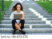 Young businesswoman having a videoconference with her laptop computer sitting on urban steps outdoors.. Middle-age businesswoman working with her laptop computer sitting on the floor. Стоковое фото, агентство Ingram Publishing / Фотобанк Лори