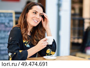 Middle-aged woman drinking coffee in an urban cafe bar. Young female sitting at table at an outside terrace. Girl with california highlights hairstyle.. Middle-aged woman using tablet on coffee break in urban cafe bar. Стоковое фото, агентство Ingram Publishing / Фотобанк Лори