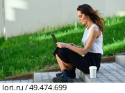 Young businesswoman having a videoconference with her laptop computer sitting on urban steps outdoors.. Middle-age businesswoman working with her laptop computer sitting on the floor. Стоковое фото, агентство Ingram Publishing / Фотобанк Лори