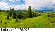 Picturesque spring Carpathians landscape panorama with an old hut in the forest and wooden split rail fence across a green and lush pasture on the valleys of Yablunytsya village, Ukraine. Стоковое фото, агентство Ingram Publishing / Фотобанк Лори