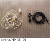 Two pairs of black and white wired headphones, for music listening. Wrap different ways, one is tangled while another neatly wrapped, as a characteristic of different human behavior, opposite concept. Стоковое фото, агентство Ingram Publishing / Фотобанк Лори