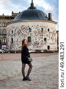 Adult Woman Poses Confidently Outdoors Near an Ancient Stone Building Against a Cloudy Sky. Стоковое фото, фотограф Aleksandr Golubev / Фотобанк Лори