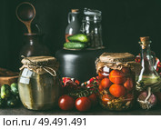 Preserving of fruits and vegetables harvest. Various preserve glass jars on dark table. Healthy way of harvest storage. Стоковое фото, агентство Ingram Publishing / Фотобанк Лори