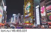 Osaka, Japan - Sep 22 2024, 4k, Panoramic view of Dotonbori river with a ship with tourists, a lot of people on embankment, there are a lot of advertising and illuminations on buildings, Osaka, Japan. Редакционное видео, видеограф Сергей Богомяко / Фотобанк Лори