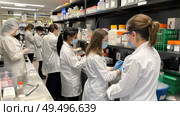 Several women wearing white lab coats are conducting experiments in a laboratory setting, surrounded by scientific equipment and specimens. Стоковое AI-изображение, AI-художник Данила Большаков / Фотобанк Лори