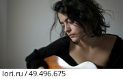 A woman holds a guitar in her right hand, showcasing her musical talent and love for playing the instrument. Стоковое AI-изображение, AI-художник Данила Большаков / Фотобанк Лори