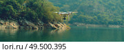A small aircraft flying above a body of water with waves below. The scene captures the plane in motion against the backdrop of the vast blue water. Стоковое AI-изображение, AI-художник Данила Большаков / Фотобанк Лори