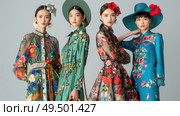 Three women of varying ethnicities wearing vibrant dresses and hats are standing side by side outdoors. Стоковое AI-изображение, AI-художник Данила Большаков / Фотобанк Лори