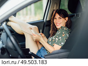 Happy woman writing in a notebook with a pen in a white car pulling her feet out the window. Female laughing and wearing flowered shirt and shorts.. Woman writing in a notebook with a pen in a white car. Стоковое фото, агентство Ingram Publishing / Фотобанк Лори