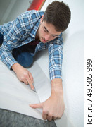 Man cutting underlay against skirting board. Стоковое фото, агентство Ingram Publishing / Фотобанк Лори