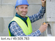 worker checks erected brick wall with level. Стоковое фото, агентство Ingram Publishing / Фотобанк Лори