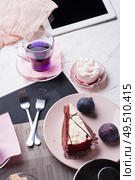 life style set at meeting in cafe.Thai blue, Butterfly pea tea served with fresh figs and panna cotta cake and fruit piece of cake on serving napkins. . Стоковое фото, агентство Ingram Publishing / Фотобанк Лори