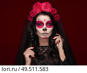 Portrait of a woman with sugar skull makeup over red background. Halloween costume and make-up. Portrait of Calavera Catrina. Стоковое фото, агентство Ingram Publishing / Фотобанк Лори