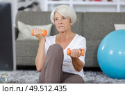 concentrated senior woman exercising with dumbbell at fitness center. Стоковое фото, агентство Ingram Publishing / Фотобанк Лори