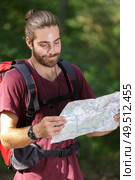 hiker man looking to map standing in forest. Стоковое фото, агентство Ingram Publishing / Фотобанк Лори