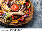 Grilled sausages and vegetables with sauce ketchup on wooden tray.Bbq food. Grilled sausages with vegetables. Стоковое фото, агентство Ingram Publishing / Фотобанк Лори