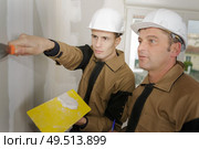 supervisor overseeing apprentice using filler on plasterboard. Стоковое фото, агентство Ingram Publishing / Фотобанк Лори