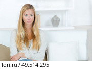 serious young woman sat at home on the sofa. Стоковое фото, агентство Ingram Publishing / Фотобанк Лори