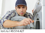 plumber fixing a washing machine. Стоковое фото, агентство Ingram Publishing / Фотобанк Лори