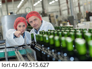 female worker pointing at the bottles in the conveyor belt. Стоковое фото, агентство Ingram Publishing / Фотобанк Лори