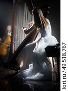 girl playing the harp on stage during a concert. Стоковое фото, агентство Ingram Publishing / Фотобанк Лори