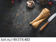 Food background with fresh parsnips roots on dark kitchen tables with knife. Top view. Vegetables cooking concept. Стоковое фото, агентство Ingram Publishing / Фотобанк Лори