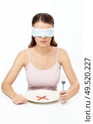 Girl blindfold sits before empty plate with an interdiction sign. Стоковое фото, агентство Ingram Publishing / Фотобанк Лори