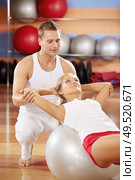 Twisting on fitball with support of the trainer. Стоковое фото, агентство Ingram Publishing / Фотобанк Лори