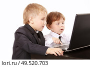 Two little boys in business suits together look in the screen of the laptop, isolated. Стоковое фото, агентство Ingram Publishing / Фотобанк Лори