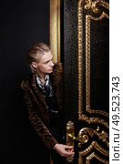 The man inserts a key into a keyhole of a black-gold door. Стоковое фото, агентство Ingram Publishing / Фотобанк Лори