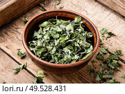 Bowl of dried oregano leaves on wooden background.Oregano or marjoram leaves. Dried oregano herb. Стоковое фото, агентство Ingram Publishing / Фотобанк Лори
