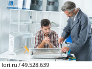 apprentice repairing appliance with his mentor. Стоковое фото, агентство Ingram Publishing / Фотобанк Лори