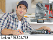 professional handyman in overalls repairing domestic dishwasher in the kitchen. Стоковое фото, агентство Ingram Publishing / Фотобанк Лори