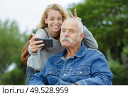 doughter and dad sitting in his wheelchair taking selfie. Стоковое фото, агентство Ingram Publishing / Фотобанк Лори