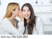 girl telling a secret in the ear of her friend. Стоковое фото, агентство Ingram Publishing / Фотобанк Лори