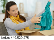 woman looking with disdain at a top delivered by courrier. Стоковое фото, агентство Ingram Publishing / Фотобанк Лори