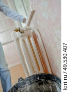 a plumber is fixing radiator. Стоковое фото, агентство Ingram Publishing / Фотобанк Лори