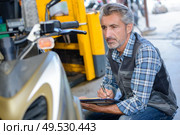 portrait of a mechanic assessing scooter. Стоковое фото, агентство Ingram Publishing / Фотобанк Лори