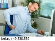 man with back pain in armchair at office. Стоковое фото, агентство Ingram Publishing / Фотобанк Лори
