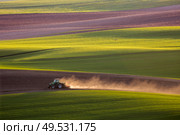 Sunset light over plowing tractor in the spring, South Moravia, Czech Republic. tractor plows the field in the spring. Стоковое фото, агентство Ingram Publishing / Фотобанк Лори