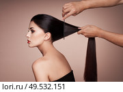 Hairdresser combs the hair of a woman. Portrait of beautiful young woman getting haircut. Care for long smooth hair. Стоковое фото, агентство Ingram Publishing / Фотобанк Лори