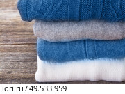folded woolen clothes close up on wooden background. woolen clothes. Стоковое фото, агентство Ingram Publishing / Фотобанк Лори