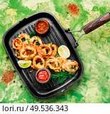 Fried calamari rings with sauce.Fast food.Fried rings of squid in the frying pan. Crispy fried squid rings. Стоковое фото, агентство Ingram Publishing / Фотобанк Лори