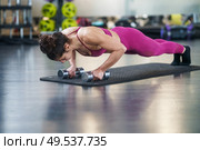 Woman doing push-ups with dumbbells in a fitness workout. Woman doing push-ups exercise with dumbbell in a fitness workout. Стоковое фото, агентство Ingram Publishing / Фотобанк Лори